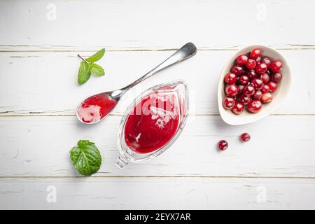 Hausgemachte Cranberry-Sauce für Fleisch und Fisch in Glas Soße Boot auf weißem Hintergrund. Draufsicht Stockfoto