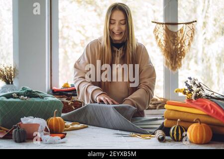 Frau wickelt Furoshiki Geschenk in Zero Waste Stil. Furoshiki Japanische Geschenkverpackung. Thanksgiving Zero Waste, umweltfreundliches Geschenkverpackungsverfahren Stockfoto