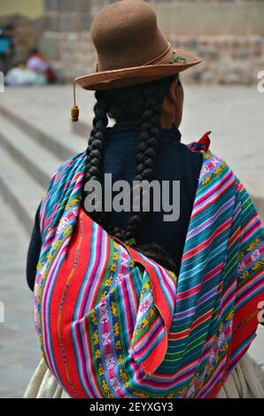 Indigene Frau mit langen schwarzen Haarflechten, traditionellen bunten Kleidern und einem braunen Filz Melone Hut auf den Straßen von Cusco Peru. Stockfoto