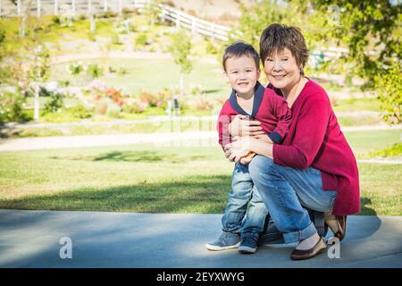 Glücklich chinesisch Großmutter mit Spaß mit sie gemischt Rennen Enkel draußen. Stockfoto