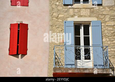 Altes Provençal Haus Steinfassade mit hellblauen und roten Fensterläden aus Holz und einem handgefertigten Eisen Balkongeländer in Saint-Rémy-de-Provence Frankreich. Stockfoto