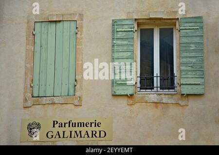 Alte Fassade eines Parfümerie-Shops mit hellgrünen Fensterläden aus Holz und einem handbemalten Schild an einer verwitterten Stuckwand in Saint-Rémy-de-Provence, Frankreich. Stockfoto