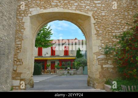 Steinbogenansicht einer Provençal großen Restaurantfassade mit einem Ziegeldach und leuchtend roten Fensterläden in Saint-Rémy-de-Provence, Frankreich. Stockfoto