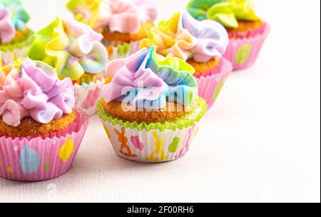 Pastell Regenbogen Frosted Ostern Cupcakes auf einer weißen Küchentisch Stockfoto