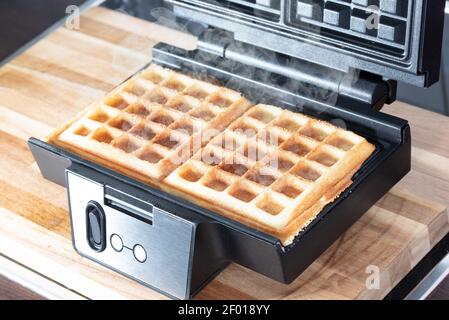 Man hat einen Blick auf die Zubereitung hausgemachter belgischer Waffeln in Waffel Hersteller Stockfoto