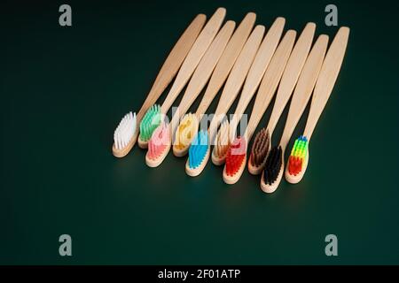 Ein Set umweltfreundlicher antibakterieller Zahnbürsten aus Bambusholz auf dunkelgrünem Hintergrund. Umwelttrends. Stockfoto