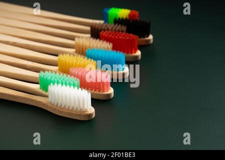 Ein Set umweltfreundlicher antibakterieller Zahnbürsten aus Bambusholz auf dunkelgrünem Hintergrund. Umwelttrends. Stockfoto