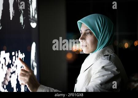 Muslimische Frau arbeitet auf Smart Infografik Bildschirm, hohe Qualität Stockfoto