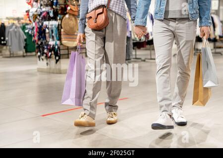 Nahaufnahme eines jungen Paares mit Einkaufstaschen, die die Hände halten Spaziergang entlang der Bekleidungsgeschäft Stockfoto