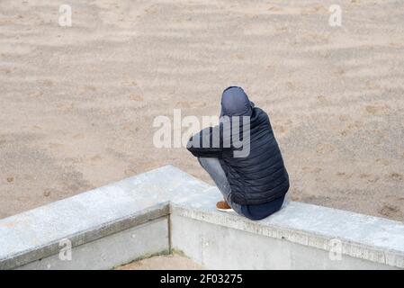 Einsame Person, die am Strand denkt Stockfoto