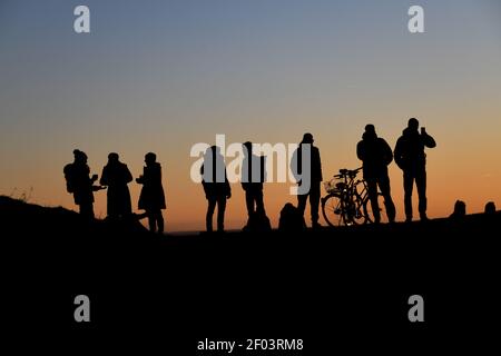 München, Deutschland. März 2021, 06th. Die Menschen stehen auf dem Olympic Hill und blicken in den Sonnenuntergang. Quelle: Tobias Hase/dpa/Alamy Live News Stockfoto