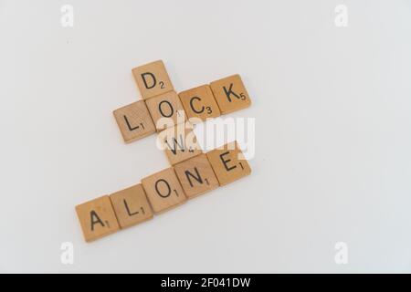 Beschriftet Spiel Holzfliesen buchstabieren heraus Lock Down und allein, das Ergebnis der Pandemie Stockfoto