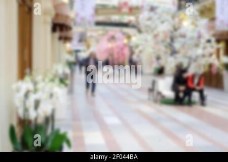 Einkaufszentrum mit Blumen dekoriert. Weiße Orchideen und blühende Bäume schmücken das Interieur für die Frühlingsferien. Unschärfe-Bild für den Hintergrund Stockfoto