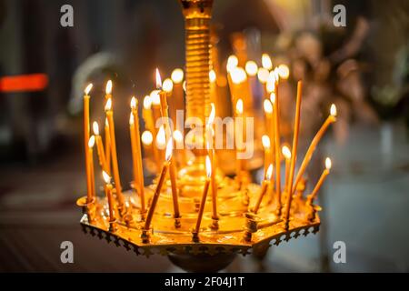 Rauch von ausgestorbenen Kerzen. Kronleuchter mit Kerzen in der Kirche. Hintergrund für Fotobücher über die Taufe. Weichfokus. Verblurkelt Stockfoto