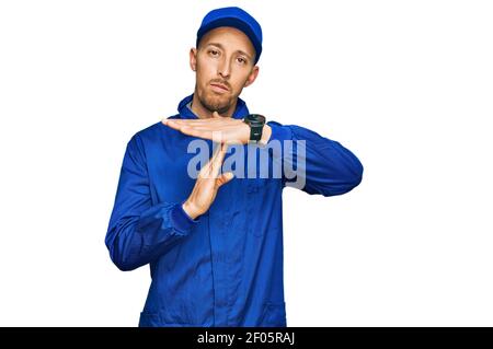 Glatze Mann mit Bart tragen Baumeister Jumpsuit Uniform tun Auszeit Geste mit Händen, frustriert und ernstes Gesicht Stockfoto