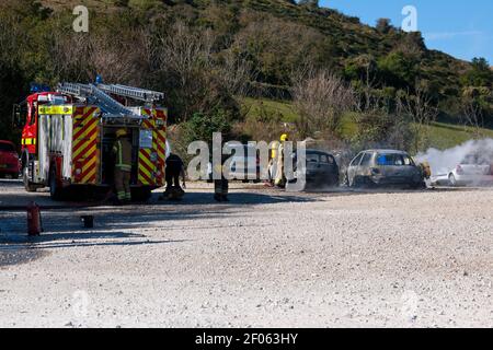 Feuerwehrleute bei EINEM Autofeuer in Lulworth Cove Dorset England VEREINIGTES KÖNIGREICH Stockfoto