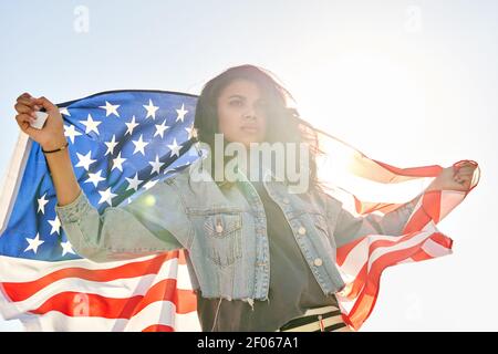 Afroamerikanische Frau, die auf der Straße steht und die Flagge der usa hält und wegschaut. Stockfoto