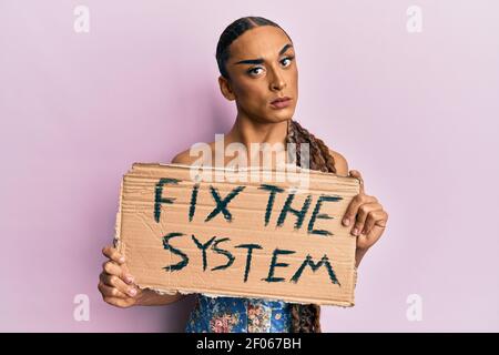 Hispanic Mann trägt Make-up und lange Haare halten fix das System Banner Karton skeptisch und nervös, runzelte wegen des Problems. Negative pe Stockfoto