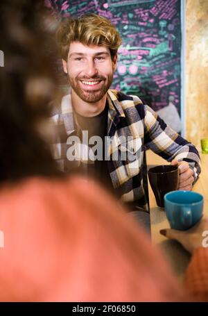 Junge fröhliche Paar in hellen Freizeitkleidung im gemütlichen Gespräch Küche und einander beim Kaffee betrachten Stockfoto