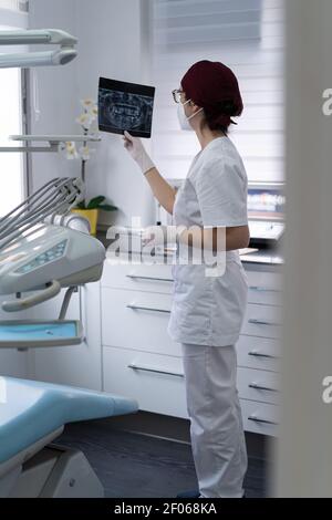Seitenansicht des wehmütigen Arztes in einheitlichem Untersuchungsbild der Radiographie Des Patienten beim Nachdenken über die Diagnose Stockfoto