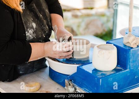 Crop anonyme weibliche Handwerker in Schürze Modellierung Ton Topf und Korrigieren der Form am Wurfrad Stockfoto