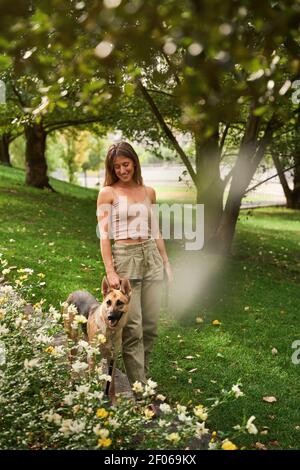Ganzer Körper von positiven weiblichen Besitzer Walking Deutsch Schäferhund Im Park Stockfoto