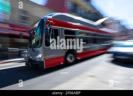 Großes graues Fahrzeug auf Asphalt Fahrbahn mit Auto entlang fahren Wohngebäude auf sonniger Straße in der Stadt auf verschwommenem Hintergrund Stockfoto