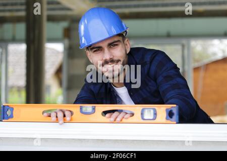 Glücklicher Baumeister, der den Holzstand auf der Baustelle überprüft Stockfoto