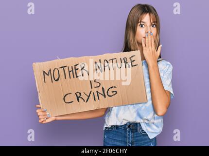 Teenager kaukasischen Mädchen hält Mutter Natur weint Protest Karton Banner über Mund mit der Hand, schockiert und Angst vor Fehler. Überrascht e Stockfoto