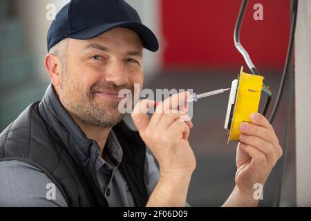 Elektriker prüft die Verkabelung am elektrischen Schalter Stockfoto