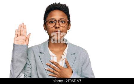 Junge afroamerikanische Frau trägt Business-Kleidung Fluchen mit Hand auf der Brust und offene Handfläche, so dass eine Loyalität Versprechen Eid Stockfoto