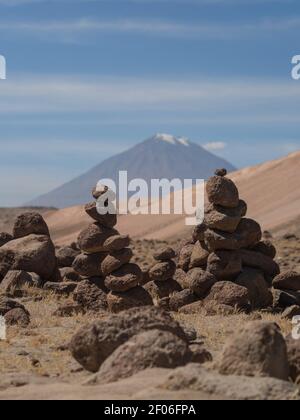 Stein cairns von Menschen gemacht Balancierturm gestapelt Felsen entlang der Straße aus Colca Canyon nach Arequipa mit Misti Vulkan im Hintergrund Peru Südamerika Stockfoto