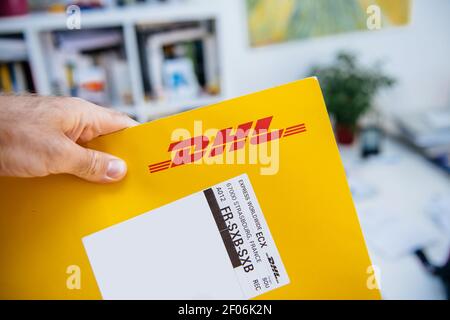 Straßburg, Frankreich - 15. Sep 2018: POV männliche Hand, die den Text auf dem Etikett eines DHL Paketbusiness-Umschlags mit SXB-Zielcode liest Stockfoto