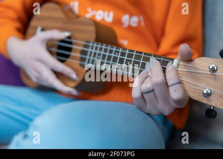 Nahaufnahme. Mädchen Hände spielen Hawaiian Musikinstrument Ukulele Stockfoto