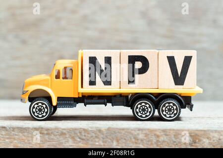 Toy truck hold alphabet letter block in word NPV (Abbreviation of net present value) on wood background Stockfoto