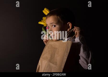 Der Junge mit Vitiligo in einem weißen Hemd und ein Fliege mit Tulpen auf schwarzem Studio-Hintergrund Stockfoto