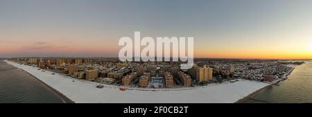 Luftaufnahme eines schneebedeckten Coney Island Beach während des Winters bei Sonnenaufgang in Brooklyn, New York. Stockfoto