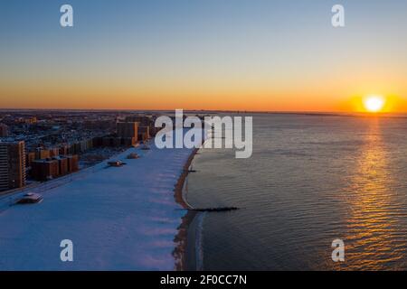 Luftaufnahme eines schneebedeckten Coney Island Beach während des Winters bei Sonnenaufgang in Brooklyn, New York. Stockfoto