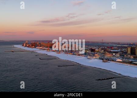 Luftaufnahme eines schneebedeckten Coney Island Beach während des Winters bei Sonnenaufgang in Brooklyn, New York. Stockfoto