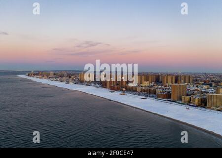 Luftaufnahme eines schneebedeckten Coney Island Beach während des Winters bei Sonnenaufgang in Brooklyn, New York. Stockfoto