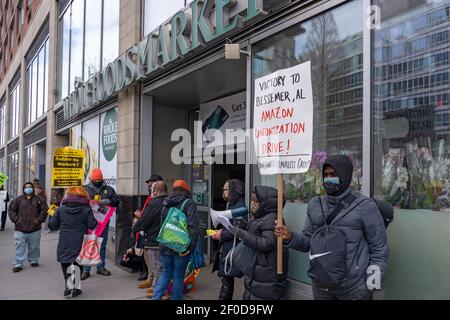 NEW YORK, NY – 6. MÄRZ: Das Wäschereizentrum und Unterstützer protestieren vor dem Whole Foods Market auf Huston zur Unterstützung der Amazonasunion von Alabama während eines Protestes von Liox Cleaners am 6. März, 2021 in New York City steht die Liox Cleaners-Kette im Gefolge des angeblichen "Gewerkschaftsbundes" vor einer Menge Opposition. Laut der verteilten Literatur, "am 19. Februar, die Liox-Wäscherei-Kette entlassen die eingewanderten Arbeiterinnen der Wash Supply Waschsalon. Kredit: Ron Adar/Alamy Live Nachrichten Stockfoto