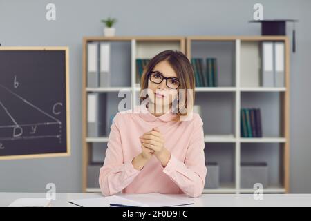 Seriöse Lehrerin sitzt am Schreibtisch und hört dem Schüler zu Virtuelle Lektion per Videoanruf Stockfoto