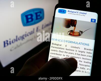 Person, die Handy mit Webseite des indischen Impfstoffunternehmens Biological E. Limited auf dem Bildschirm vor dem Logo hält. Fokus auf der Mitte des Telefondisplays. Stockfoto