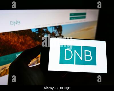 Person, die Smartphone mit dem Logo des norwegischen Finanzdienstleisters DNB ASA auf dem Bildschirm vor der Website hält. Konzentrieren Sie sich auf die Telefonanzeige. Stockfoto