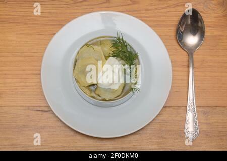 Hausgemachte Knödel mit Sauerrahm und Dill in weißem Teller auf dem Tisch. Blick von oben, serviert. Stockfoto
