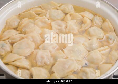 Hausgemachte Knödel werden in Kochtopf mit kochender Brühe gekocht. Nahaufnahme. Selektiver Fokus. Stockfoto