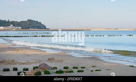 Ufer der Ostsee am Abend bei Sonnenuntergang. Weicher Sand und Surfen mit weißem Schaum auf Wellen. Breiter Schwenk-Frame-Hintergrund, selektiver Fokus. Stockfoto