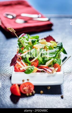 Frischer gemischter Salat mit Endivien und Kirschtomaten auf schwarze Platte Speisen, Olivenöl gießen Stockfoto