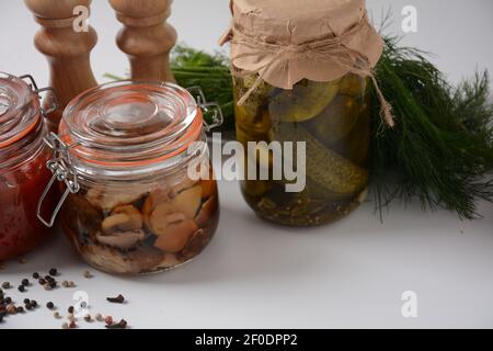 Gläser mit hausgemachtem eingelegtem Gemüse: Gurken, Tomaten, Honig-Agarik-Pilze, auf weißem Hintergrund. Marinierte und fermentierte Lebensmittel. Fermentierte Prese Stockfoto