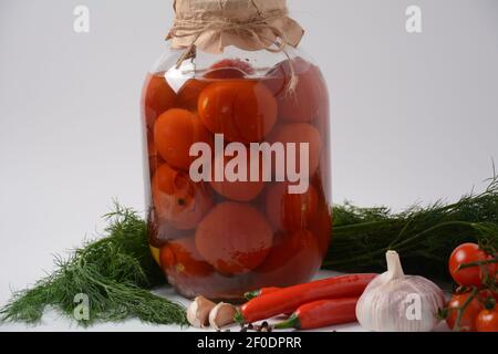 Glas mit hausgemachten eingelegten Tomaten auf weißem Hintergrund. Marinierte und fermentierte Lebensmittel. Fermentierte konservierte vegetarische Nahrung Konzept. Stockfoto